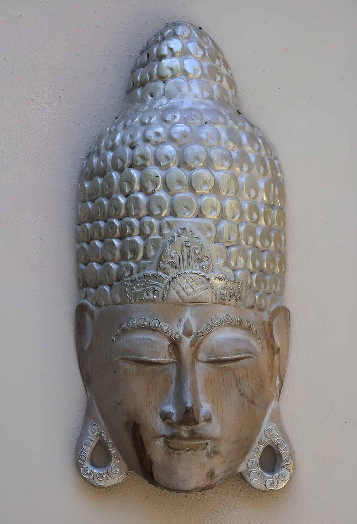Buddhamaske i træ med et stille smil