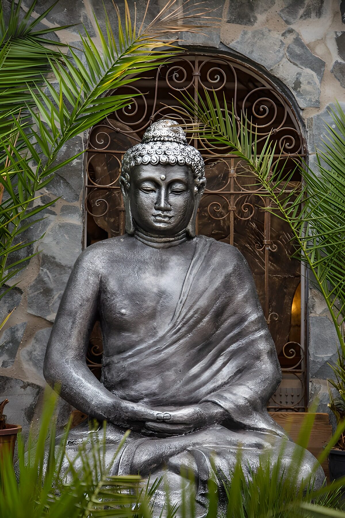 Buddhastatue mellem grønne palmeblade