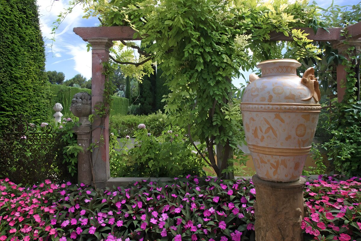 Frodig have med urne og lyserøde blomster