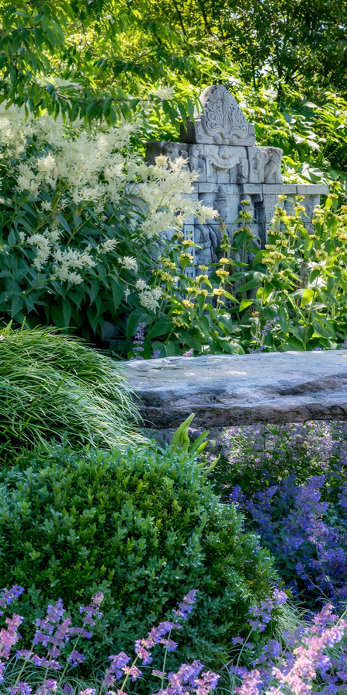 HPDK84561: Stenornament i et frodigt blomsterbed