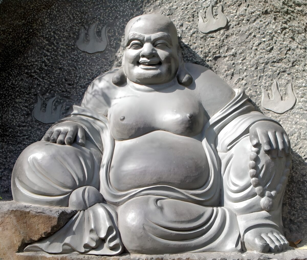 Smilende Buddha foran den rå klippe