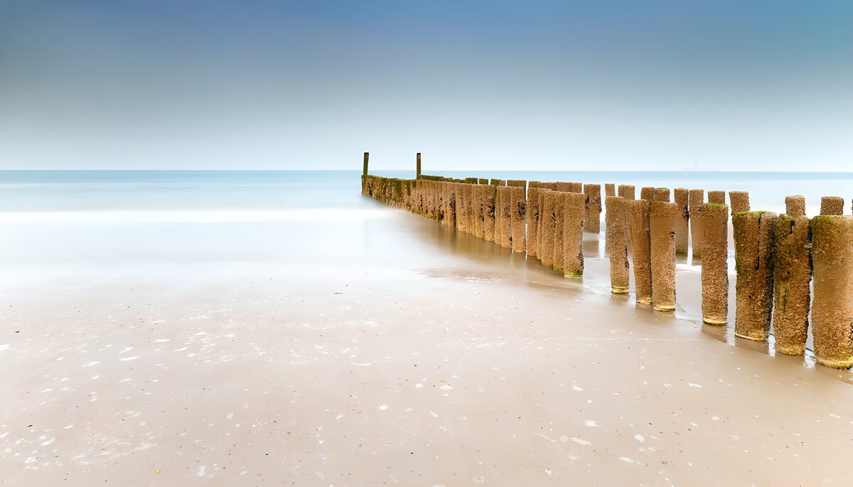 HPDK54005: Træpæle og stille vand ved stranden