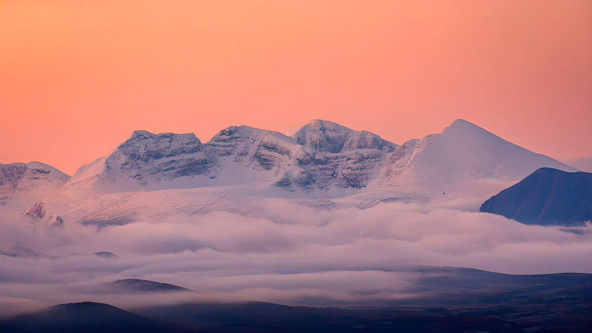Sneklædte bjerge under koralrosa himmel