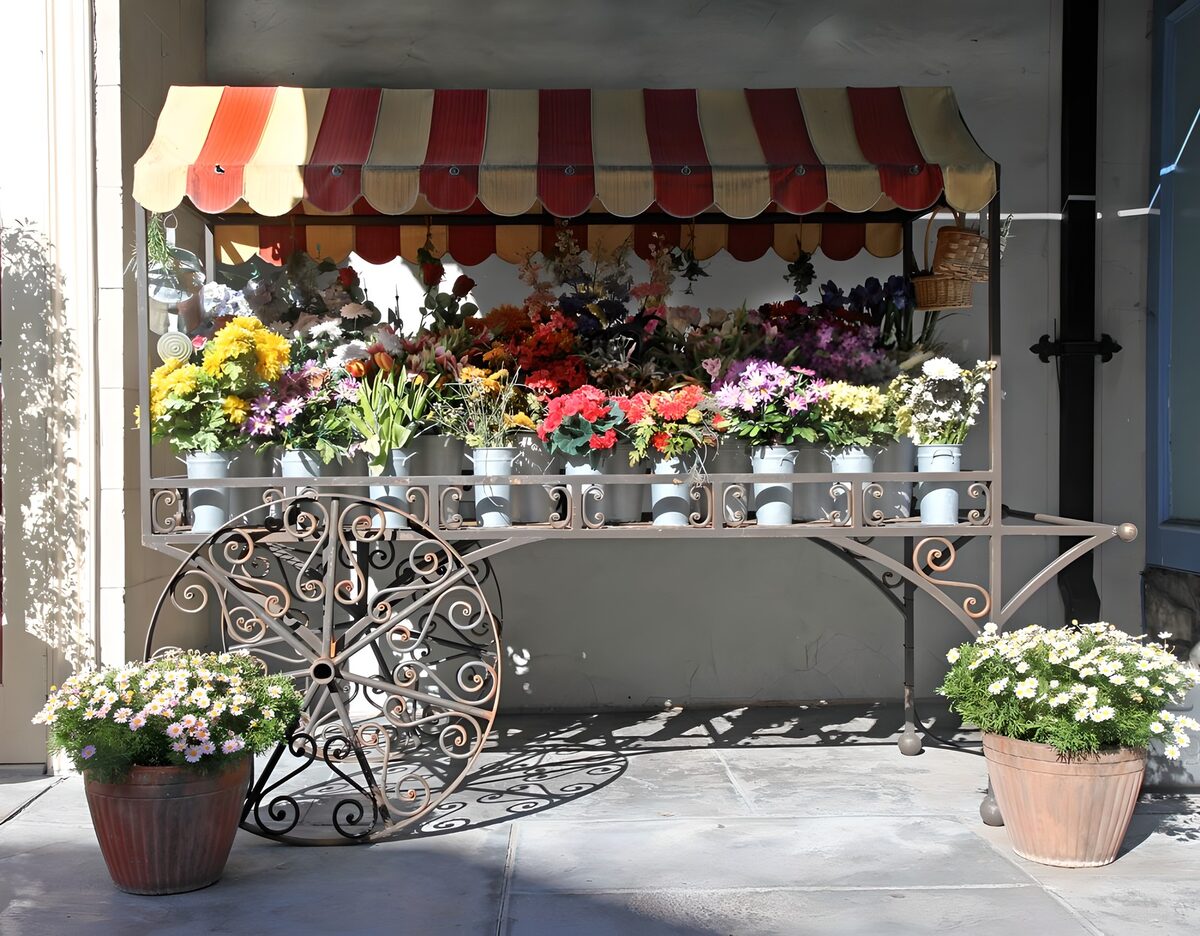 Blomstervogn under rødstribet markise
