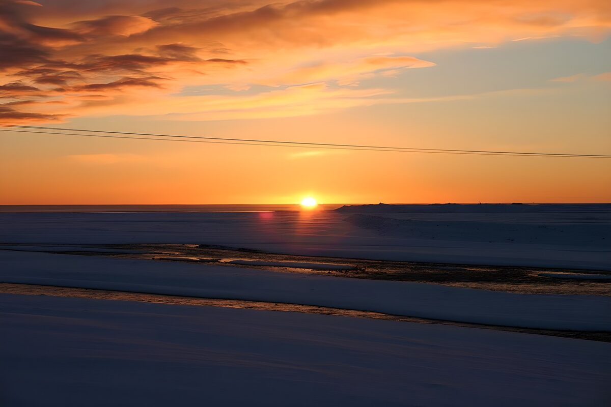 Solnedgang over sne og stille vand