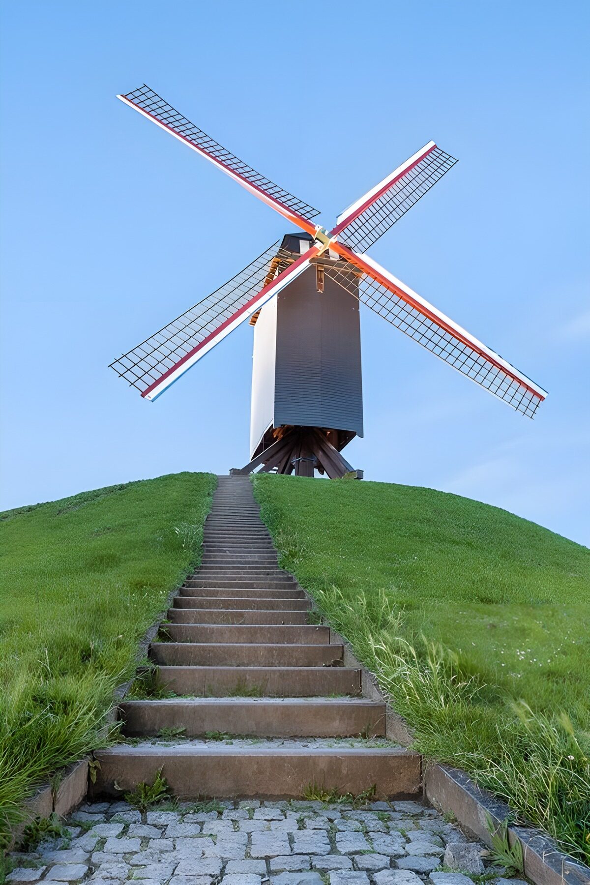 Vindmølle på grøn bakke under blå himmel