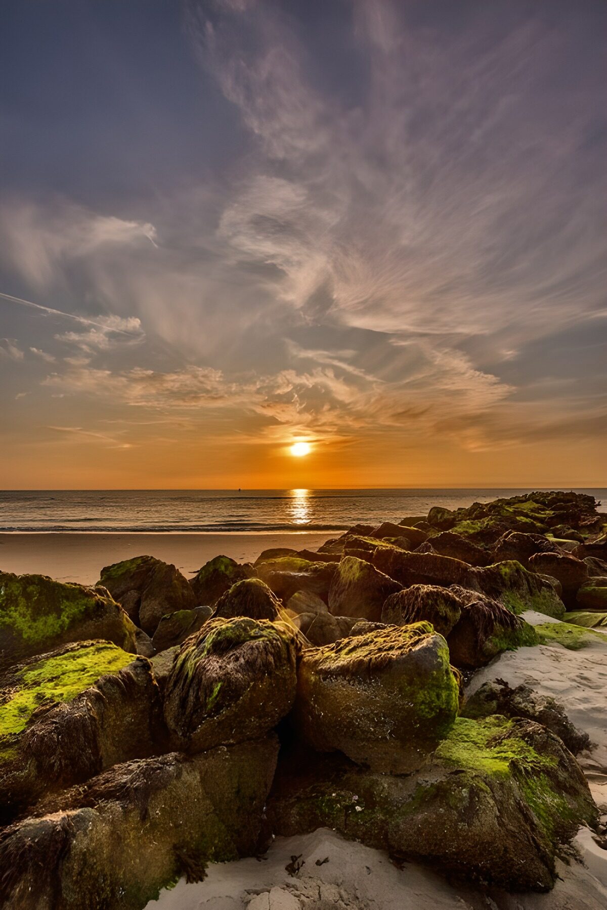 Solnedgang over strandens mørke klipper