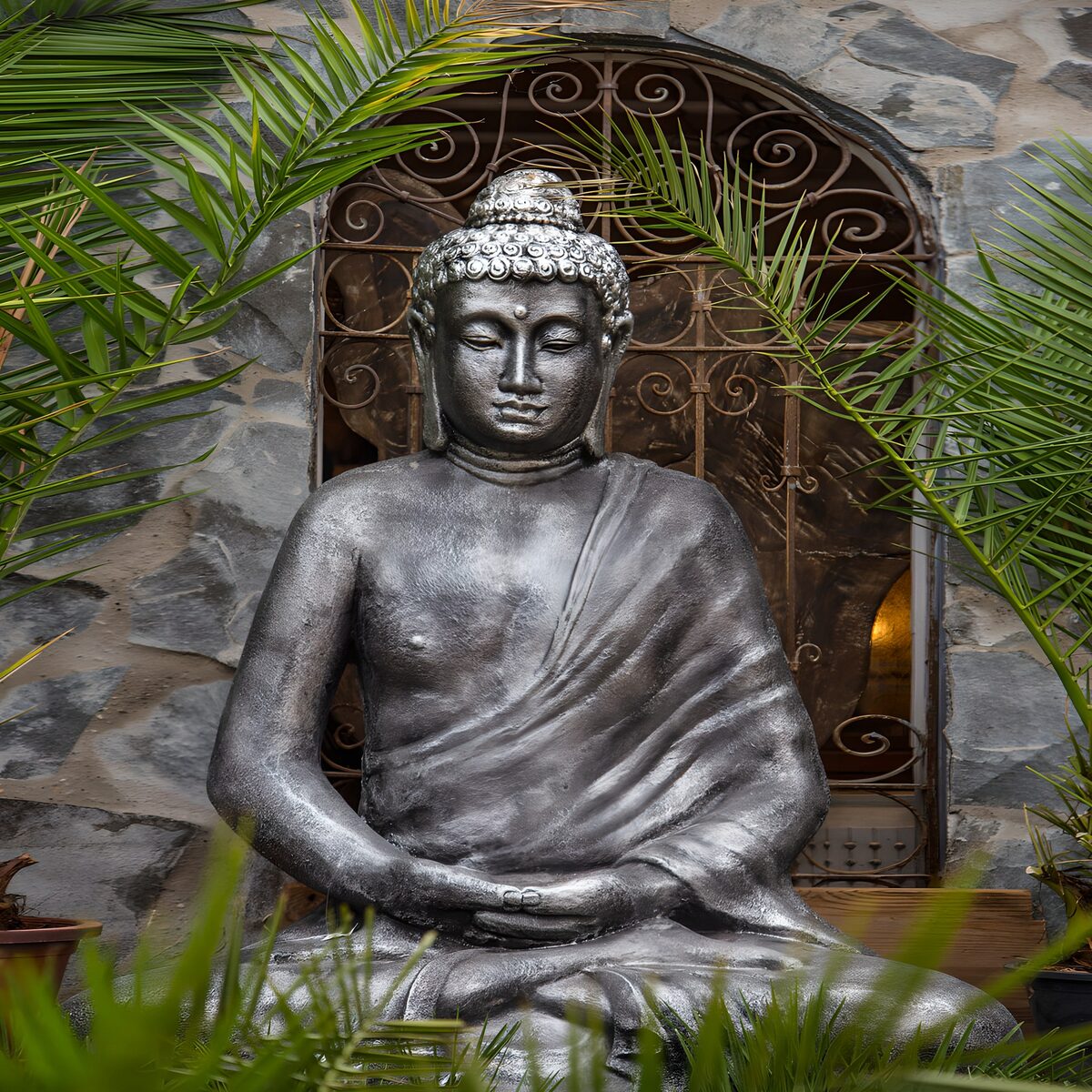 Grå Buddha omgivet af grønne palmer