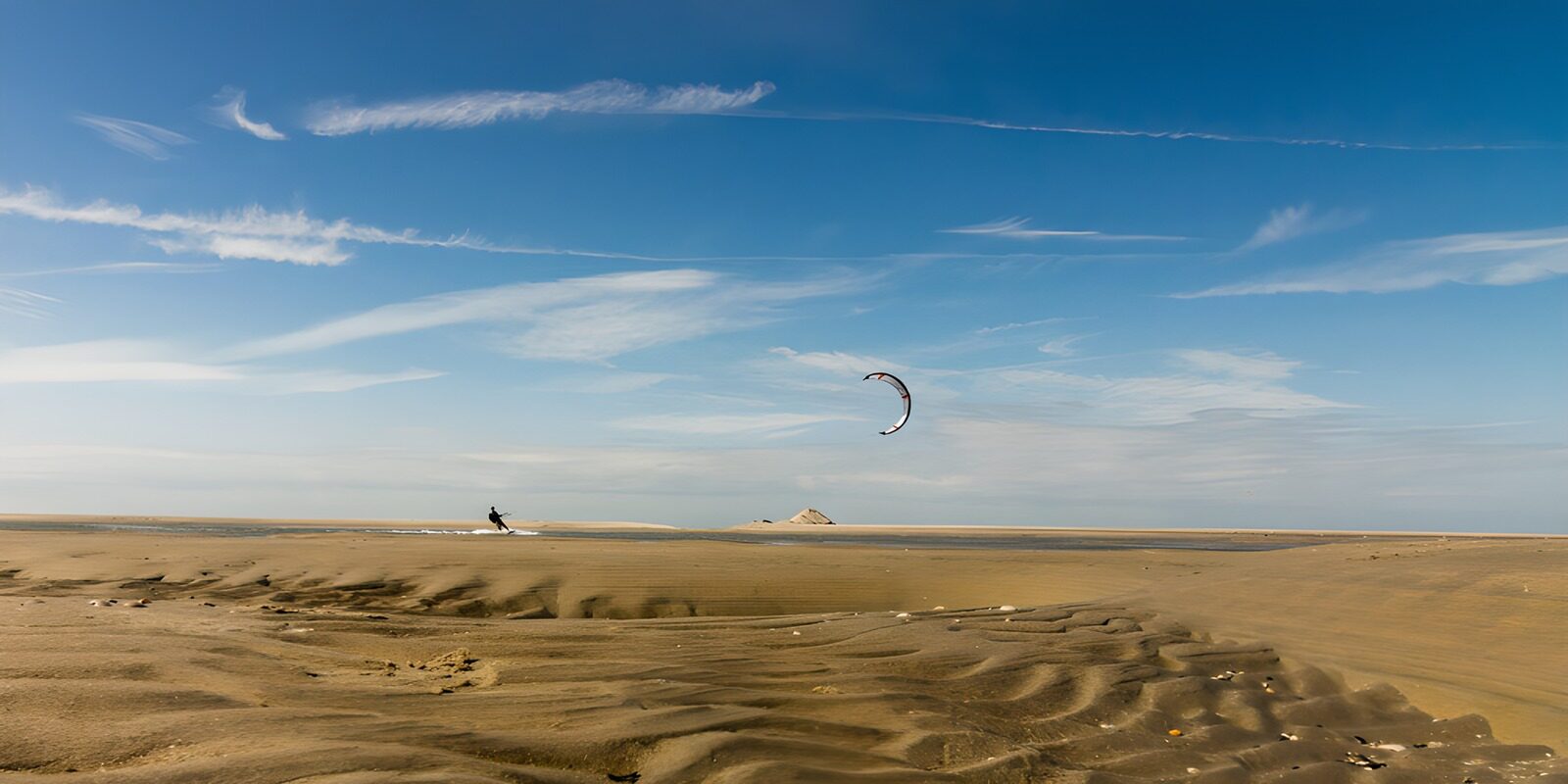 HPDK97109: Kitesurfer ved stranden under blå himmel