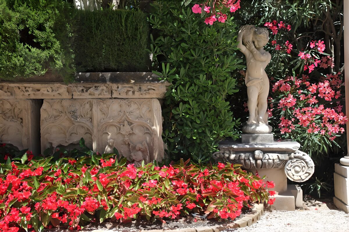 HPDK51210: Barnestatue blandt røde og rosa blomster
