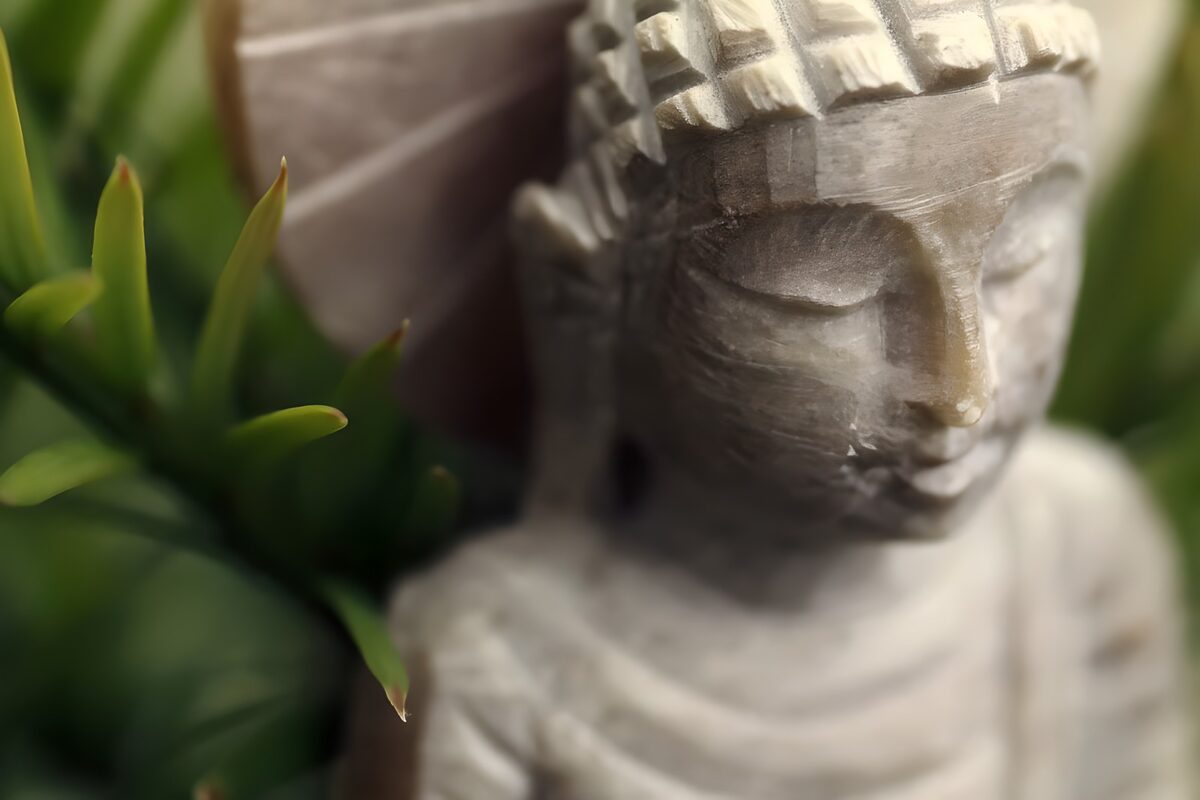 Grå Buddha omgivet af grønne blade