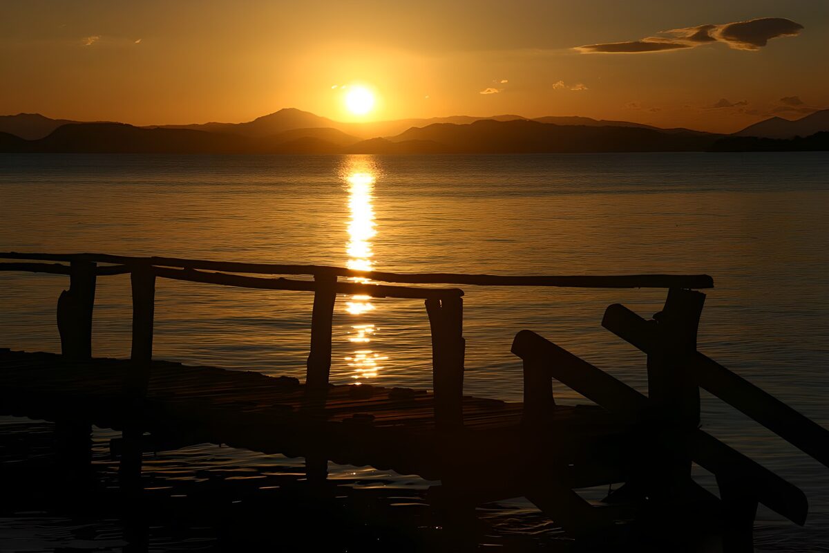 Solnedgang over vand med træbro