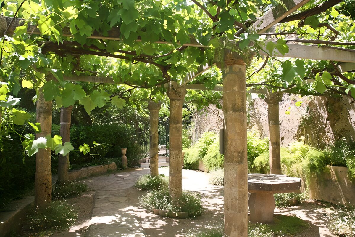 Pergola med stensøjler i sol og skygge