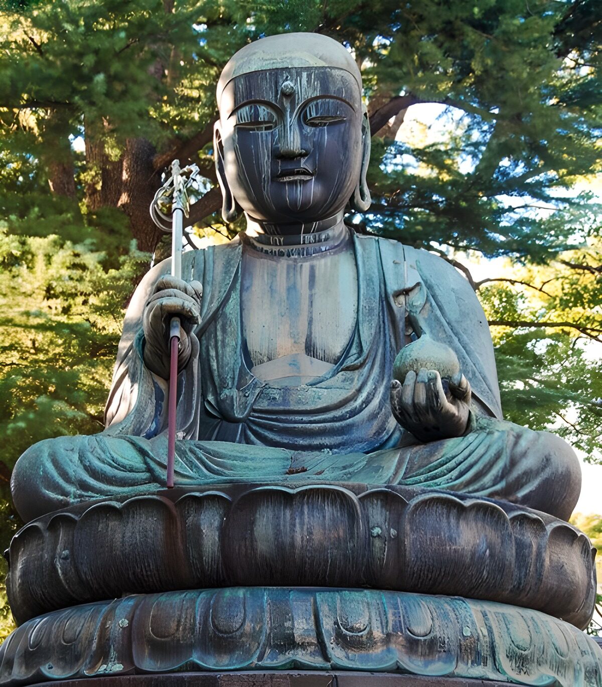 Siddende buddhastatue i træernes skygge