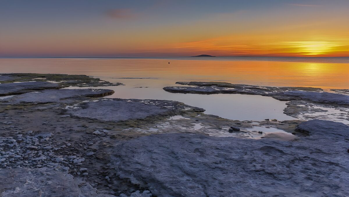 Flade klipper ved havet i solnedgang