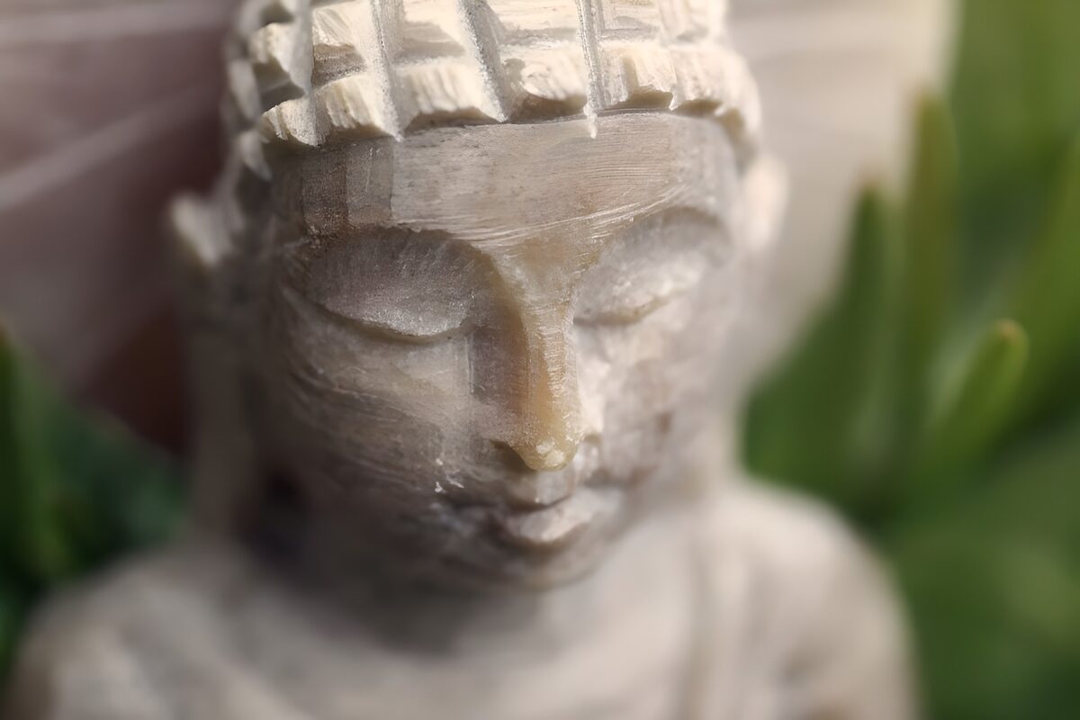 Lys buddhastatue blandt grønne blade