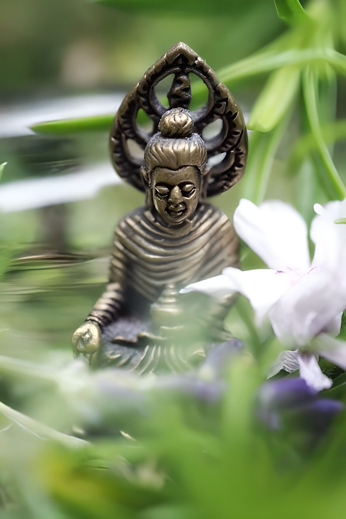 Bronzefarvet Buddha blandt blade og blomster